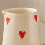 Close-up of handpainted red heart design on ceramic jug