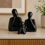 Black glossy ceramic family sculpture set displayed on a wooden shelf