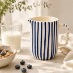 Blue striped ceramic jug displayed on a dining table with tableware