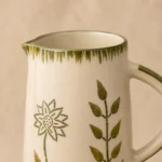 Close-up of the handpainted botanical design and glossy glaze on a handmade ceramic water jug