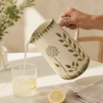 Handmade ceramic water jug serving fresh juice on a modern dining table