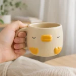 Hand holding compact 220 ml ceramic duck mug showing its comfortable rounded handle