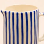 Close-up of the handpainted blue vertical stripe design on a ceramic jug