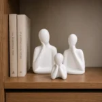 White ceramic family sculpture set displayed on a wooden shelf