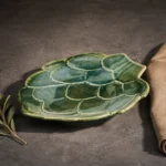 Side view of green artichoke ceramic serving platter with raised pedestal base