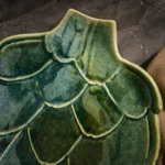 Close-up of layered green glaze and sculpted leaves on handmade artichoke ceramic platter